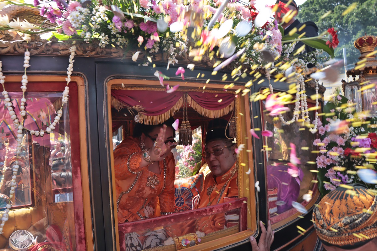 Permaisuri sebar uang dari dalam kereta kencana.
