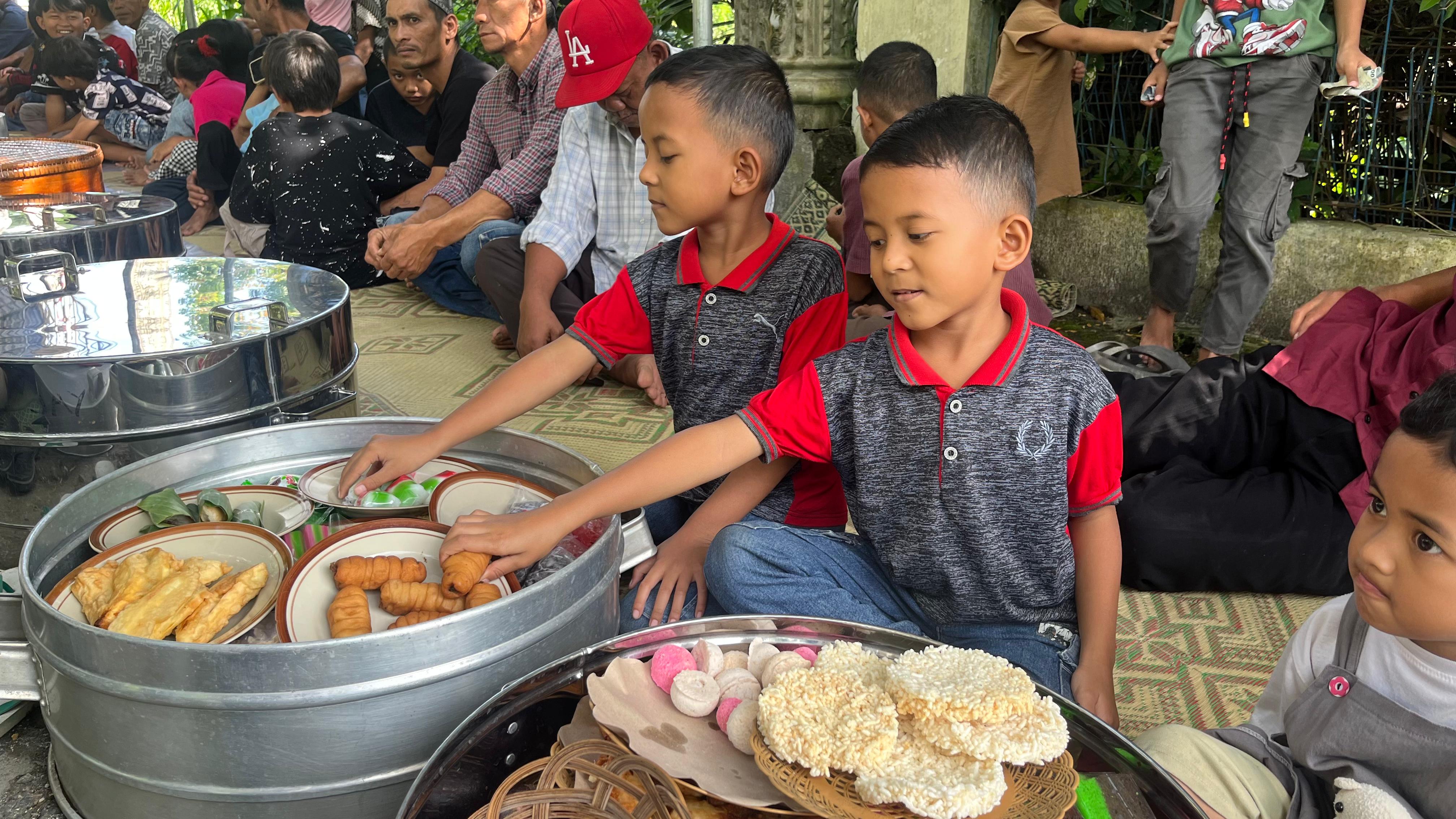 Anak-anak menikmati jajanan tradisional yang diwadahi tenongan pada tradisi sadranan di Dukuh Plukisan, Desa Sumbung, Kecamatan Cepogo, Selasa (11/2/2025).