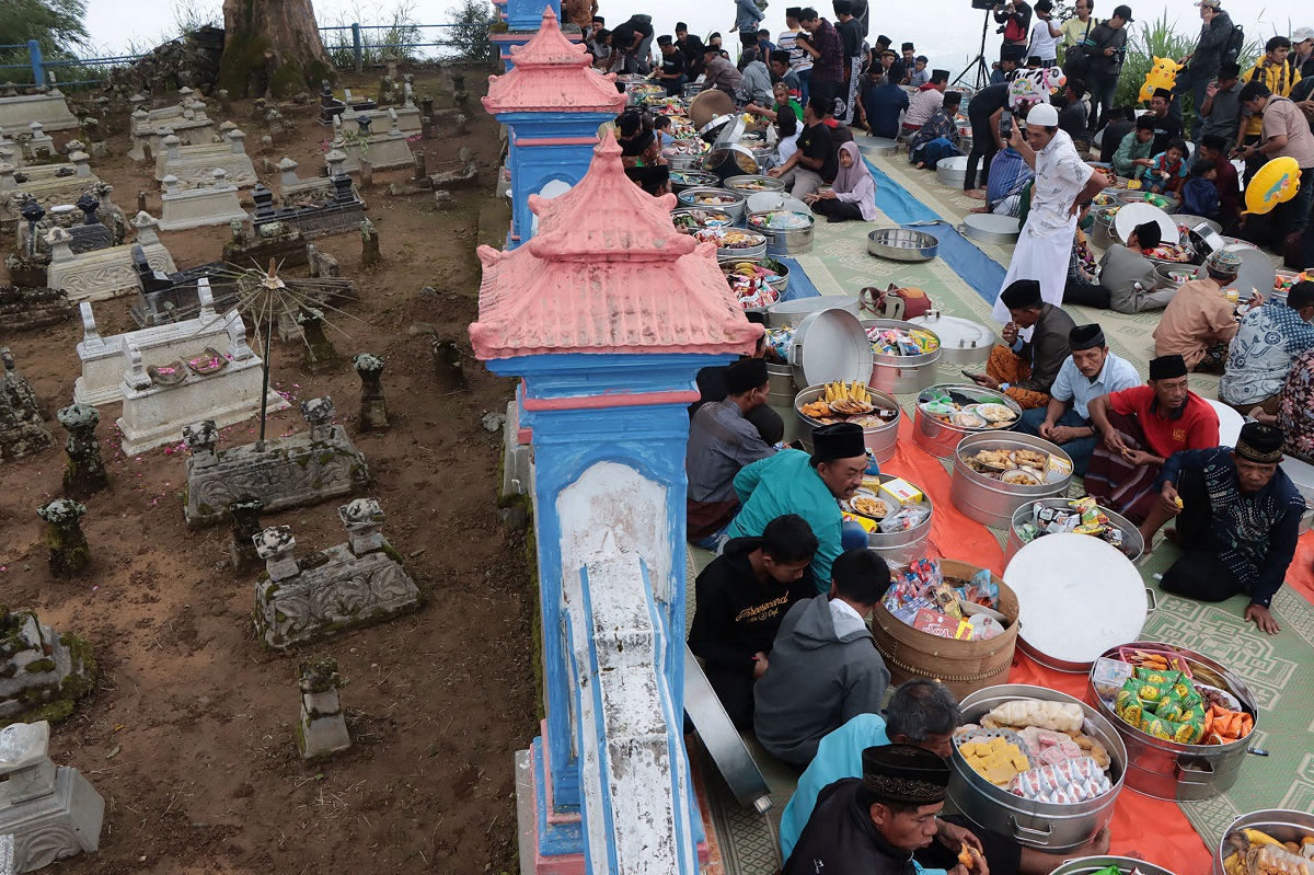 Doa bersama di area makam sebelum menyantap makanan tradisional.