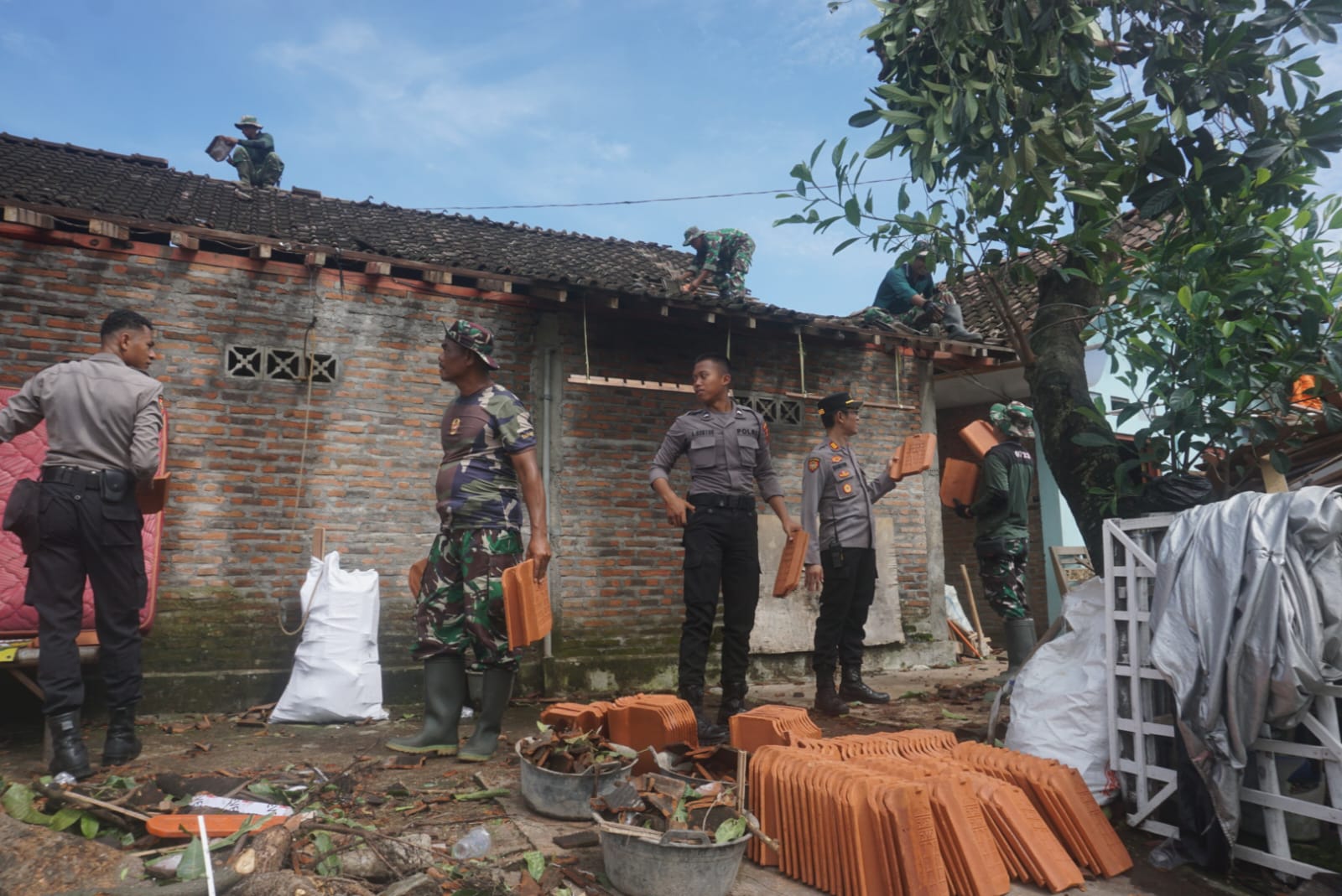 Jajaran personel TNI, Polri dan relawan saat melakukan perbaikan terhadap genteng rumah warga Desa Jambu Kulon, Ceper, Klaten yang rusak akibat angin lisus, Selasa (25/2/2025).