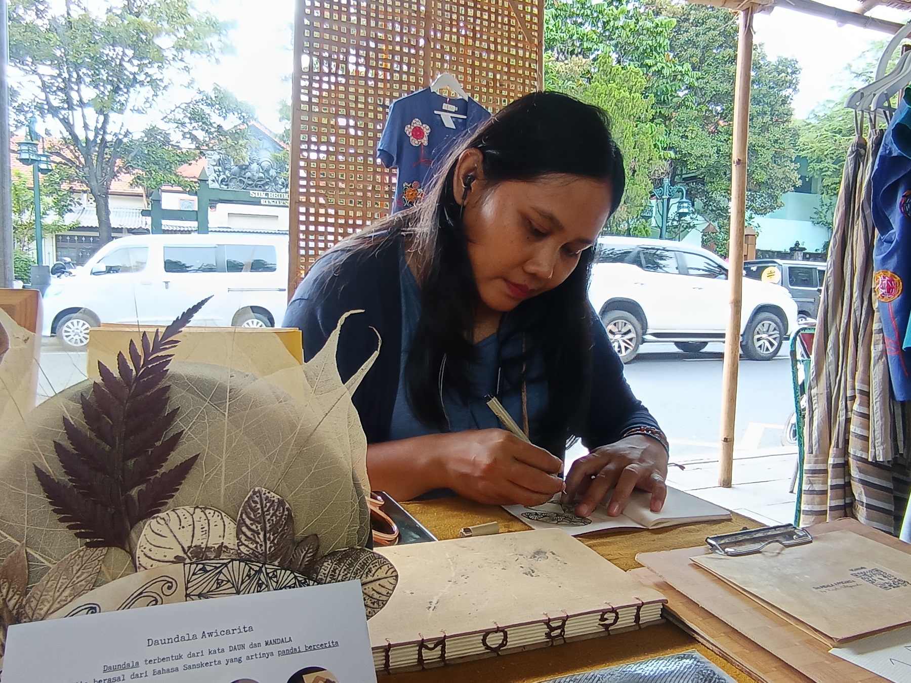 Prapti Alpandi menggoreskan lukisan di atas daun kering. (A Christian/Radar Solo)