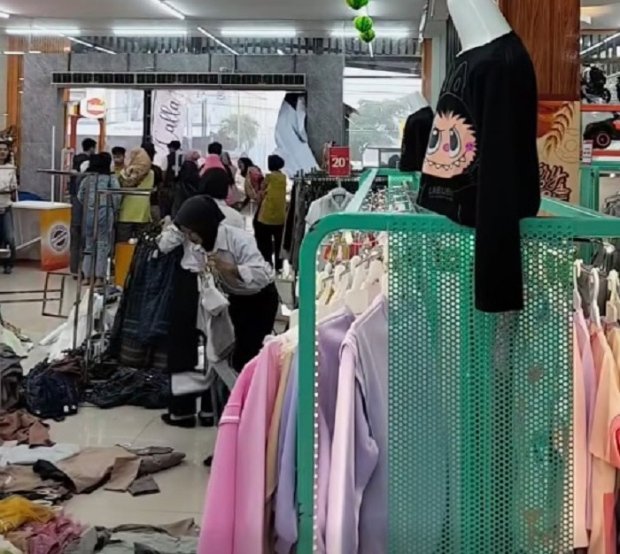 Pekerja Mitra Swalayan Bejen memungut dagangan baju yang kocar-kacir akibat dihempas hujan disertai angin kencang, Minggu (23/3/2025).