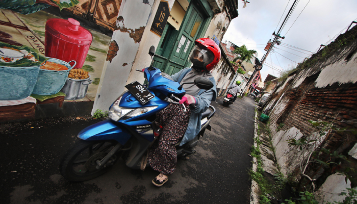 Warga melintasi deretan bangunan kuno di salah satu gang di Kampung Kemlayan, Solo.