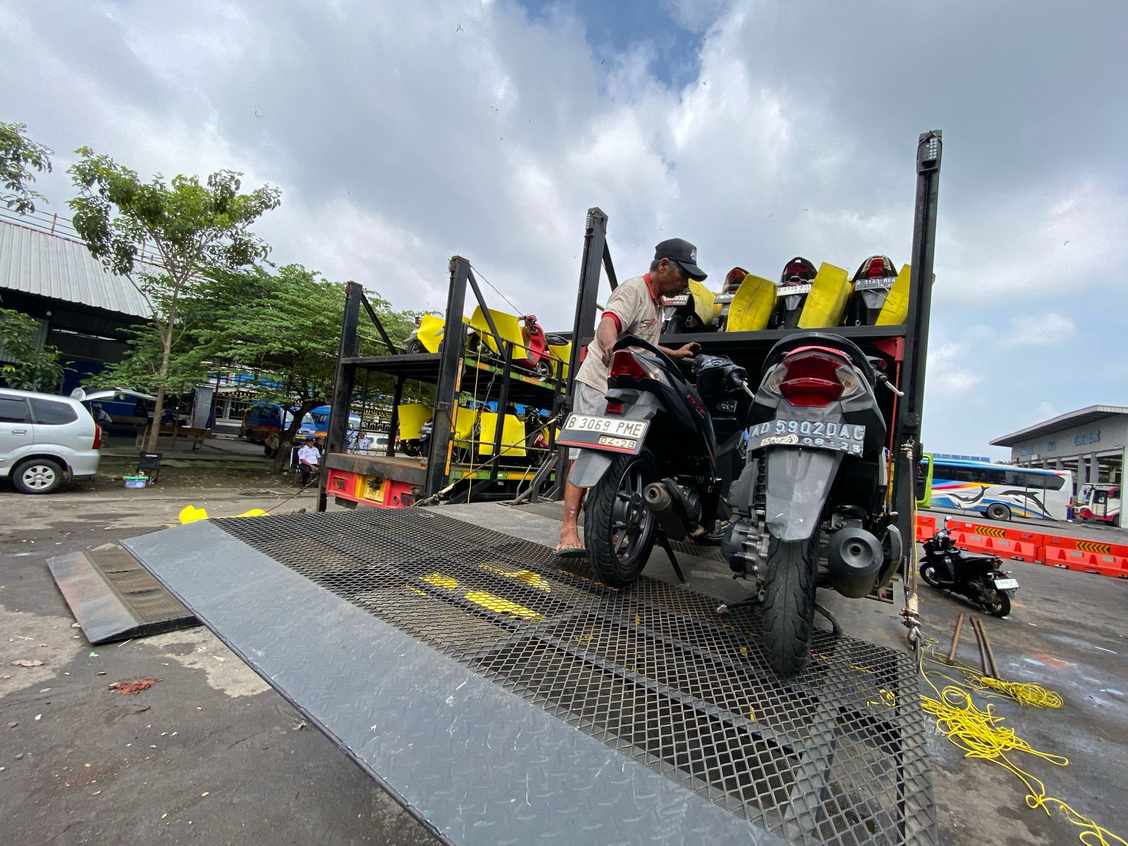 Petugas menurunkan sepeda motor milik pemudik yang ikut dalam program mudik gratis Kementerian Perhubungan (Kemenhub) dan Dishub Pemprov DKI Jakarta di Terminal Tirtonadi Kota Solo, Kamis (27/3/2025).