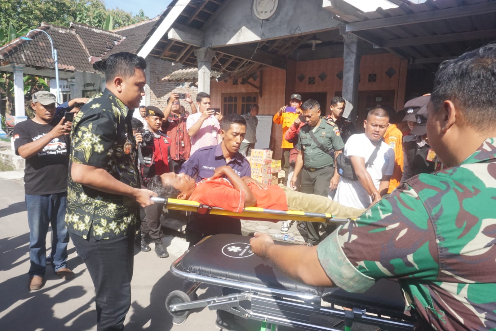 Bupati Klaten Hamenang Wajar Ismoyo  (kiri) membantu mengevakuasi korban dugaan keracunan ke ambulans di Desa Karangturi, Kecamatan Gantiwano, Selasa (15/4/2025).&nbsp;