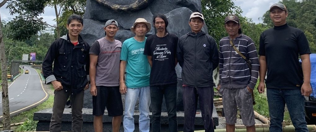 Rejo Arianto (tengah) maestro pembuatan patung biawak di Wonosobo bersama timnya berfoto di lokasi pembuatan patung dengan latar belakang Jembatan Miawak (kiri).