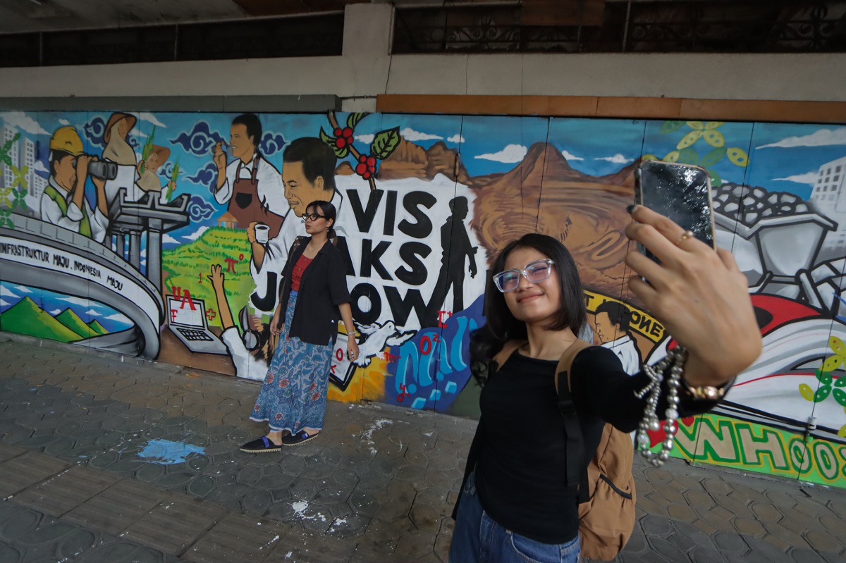 Remaja berpose di depan mural di Jalan Slamet Riyadi. Tempat ini dilintasi BST Koridor 1.