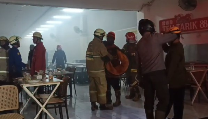 Petugas Dinas Damkar Solo berjibaku dengan asap tebal usai kebakaran di kedai Teh Tarik 88, Singosaren, Kemlayan, Serengan, Solo, Kamis (12/6/2025) malam.