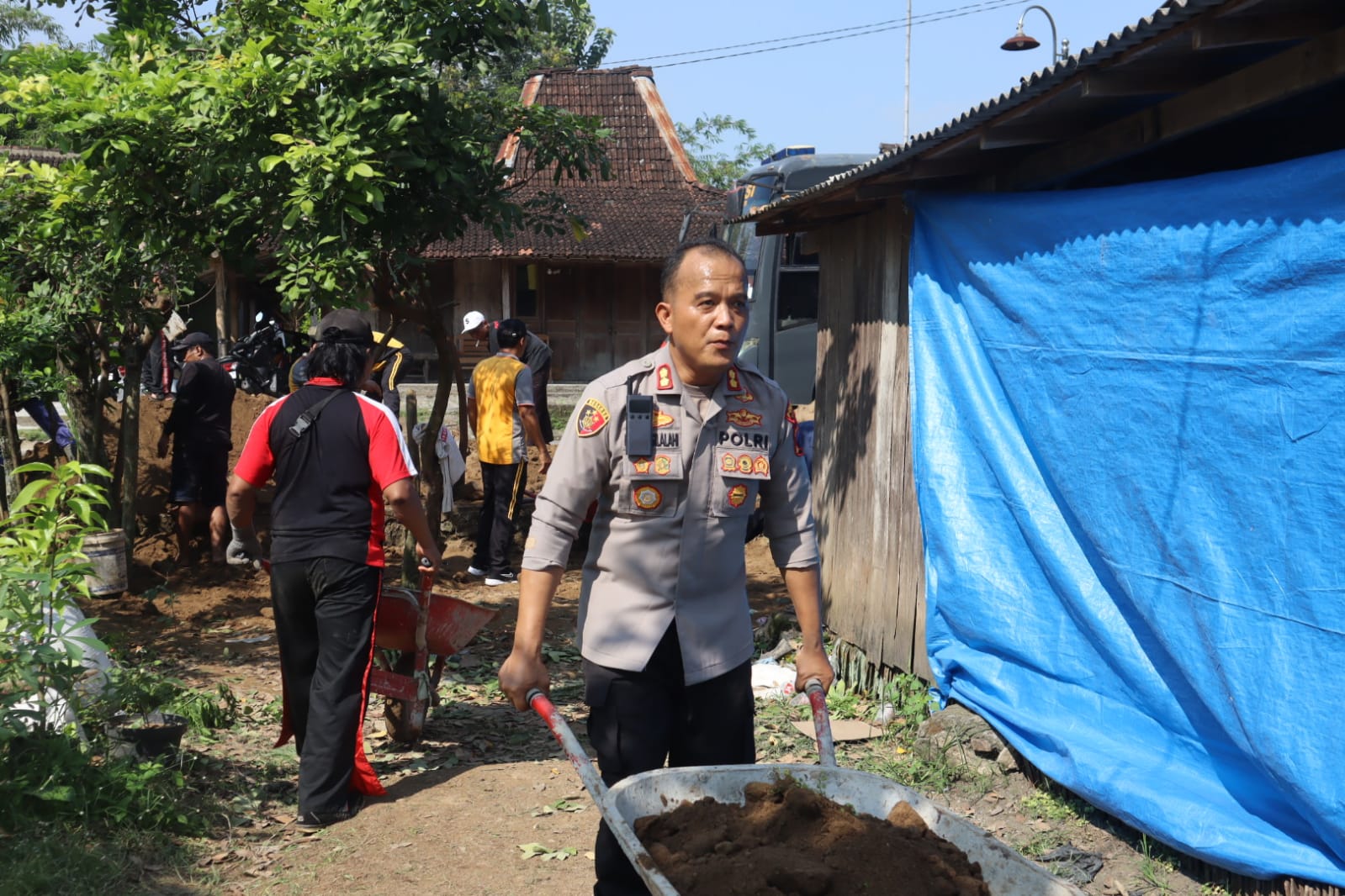 Kapolres Sragen AKBP Petrus Parningotan Silalahi ikut membantu rebah rumah warga Jepang Hari Bhayangkara ke-79. (Ahmad Khairudin/Radar Solo)