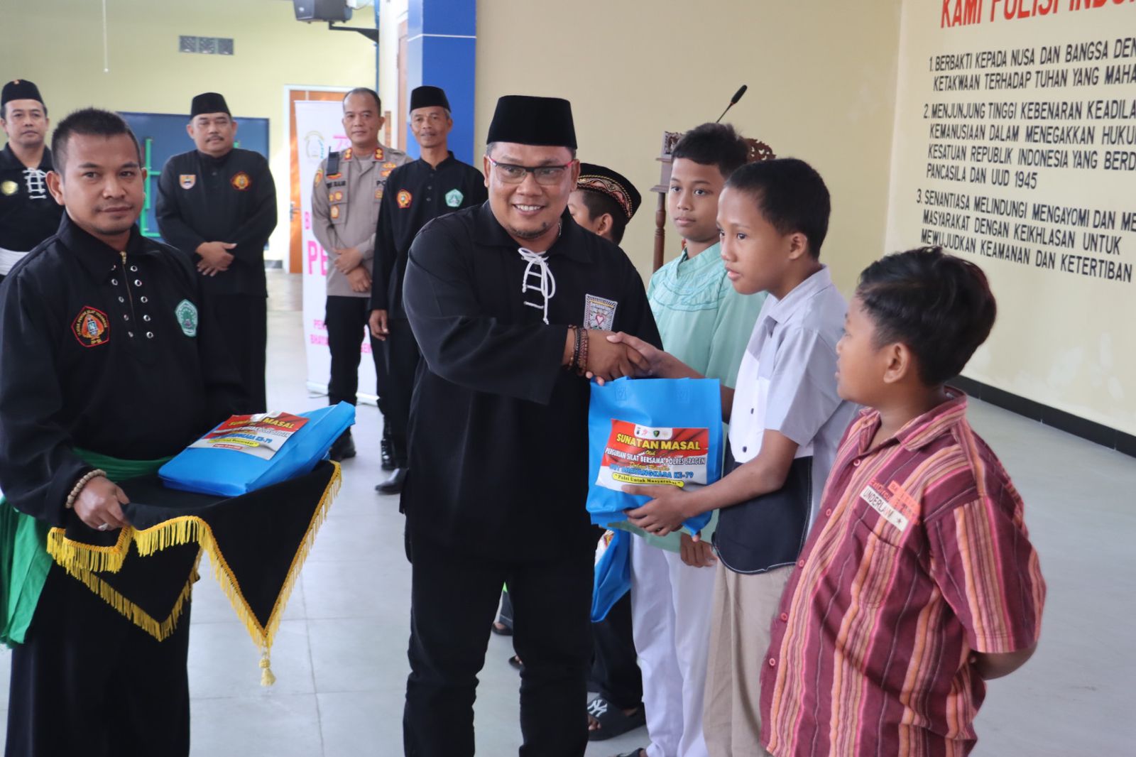 Sejumlah pengurus perguruan silat di Sragen serahkan bingkisan ke peserta sunat masal Hari Bhayangkara Ke-79 yang difasilitasi Polres Sragen, Kamis (19/6/2025). (Ahmad Khairudin/Radar Solo)