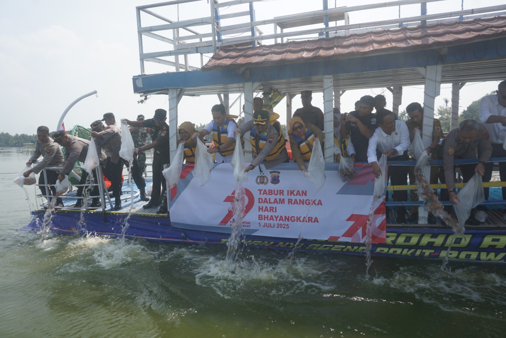 Kapolres Klaten AKBP Nur Cahyo Ari Prasetyo bersama Forkompimda Klaten tebar benih ikan nila di Rowo Jombor, Senin (23/6/2025). (Angga Purenda/Radar Solo)