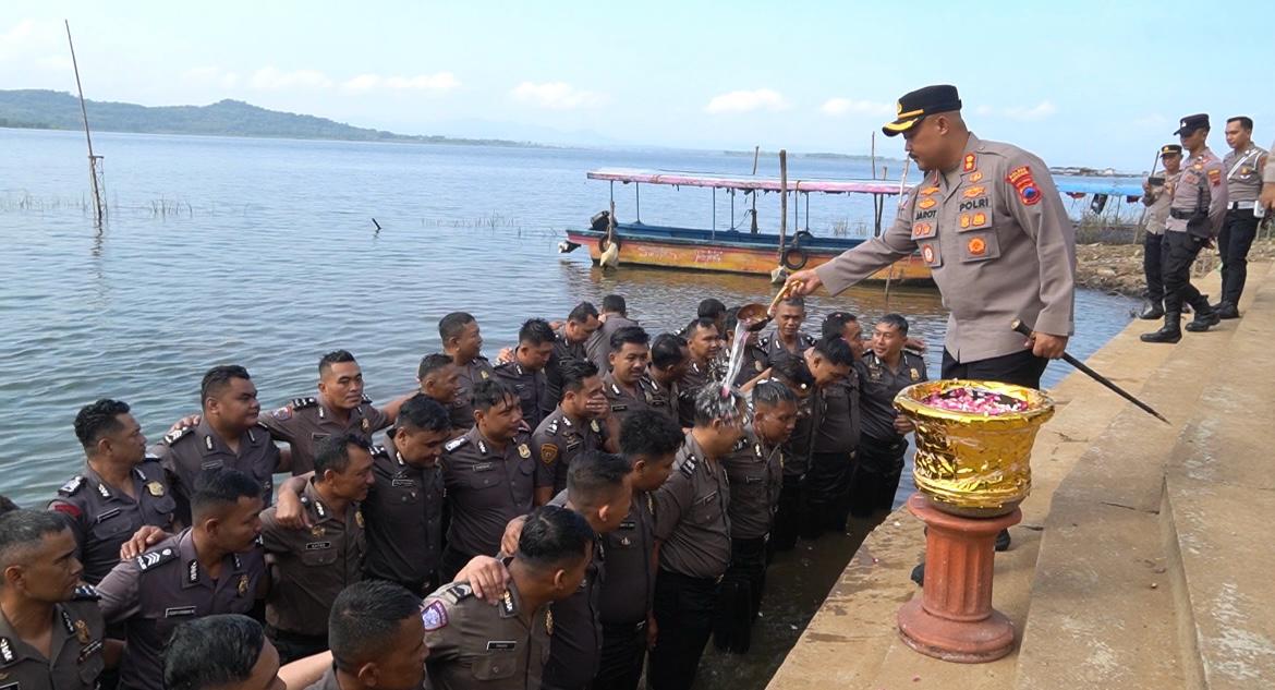 Kapolres Wonogiri AKBP Jarot Sungkowo siramkan air kembang kepada anggota yang naik pangkat di Waduk Gajah Mungkur, Senin (30/6/2025).