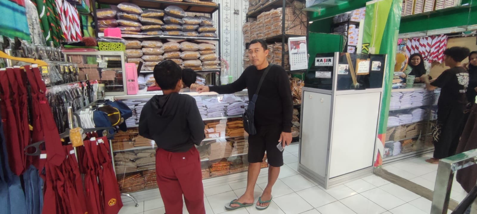 Salah seorang siswa ditemani orang tuanya membeli seragam di Pasar Kota Sragen. (Ahmad Khairudin/Radar Solo)
