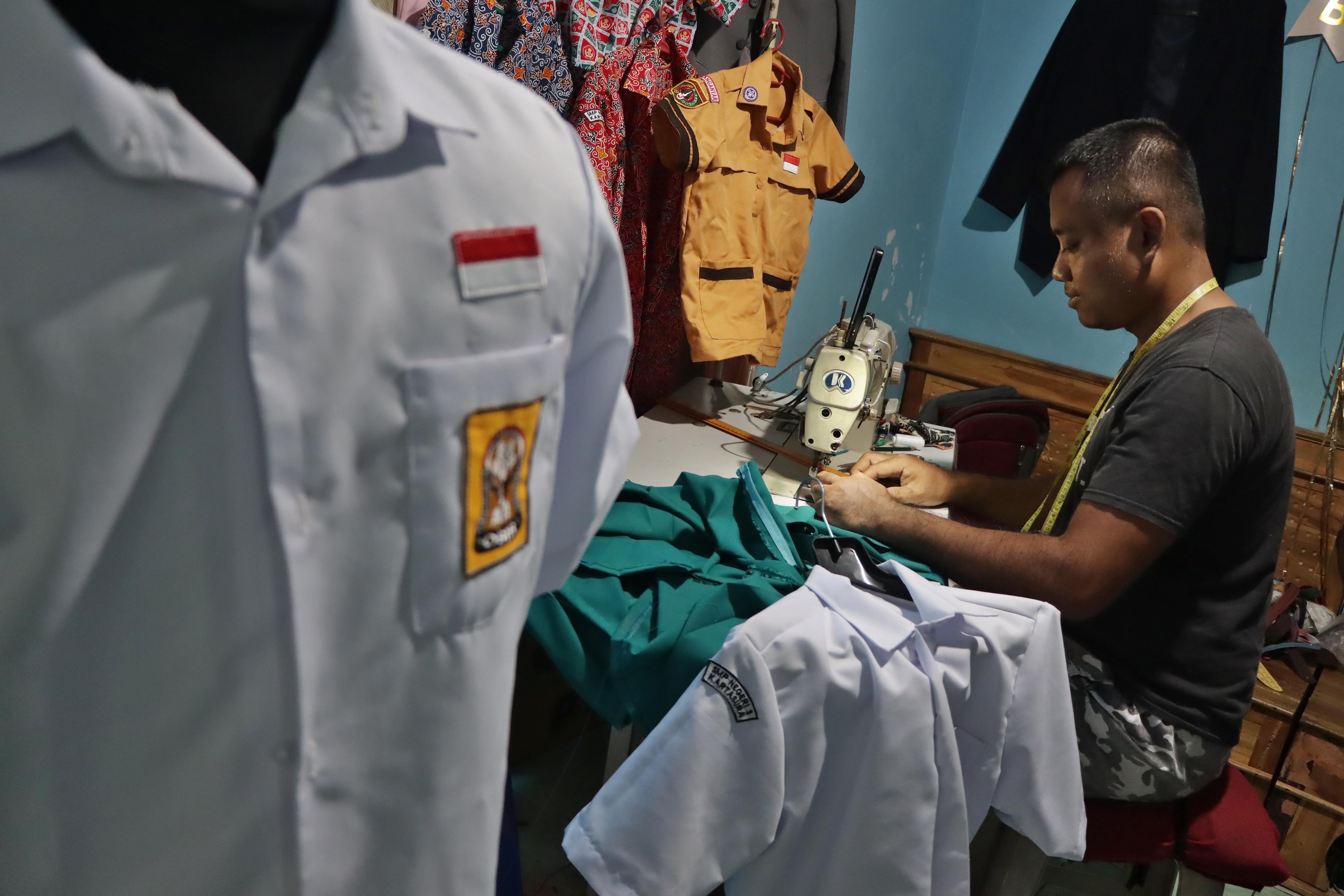 Salah seorang penjahit di Desa Bolon, Kecamatan Colomadu, Karanganyar mengerjakan pesanan seragam sekolah anak yang naik di tahun ajaran baru ini. (Arief Budiman/Radar Solo)