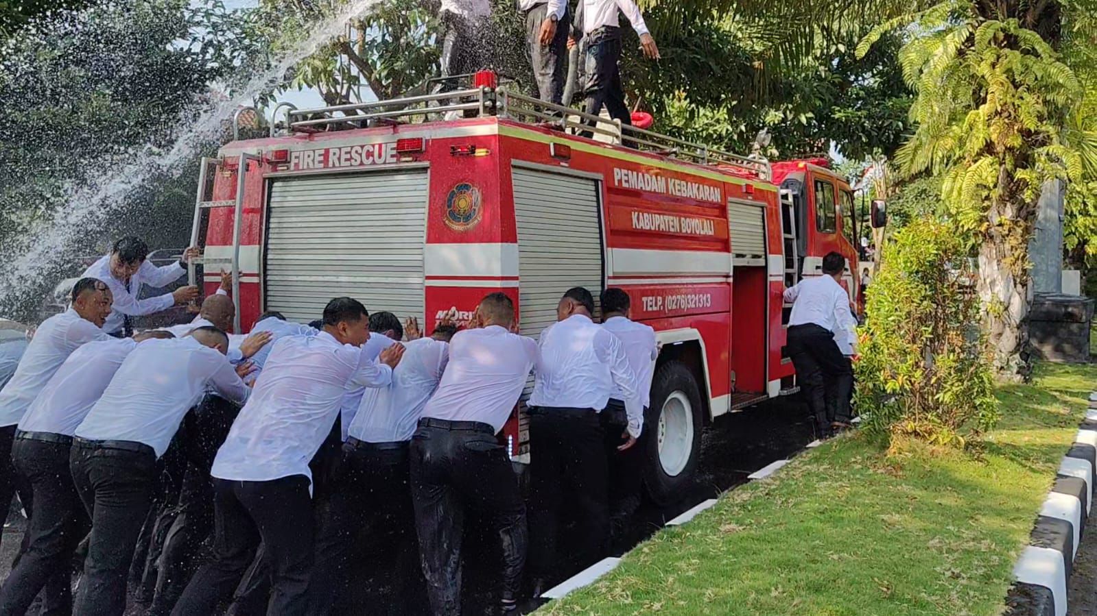 Selebrasi personel Damkar Boyolali yang dilantik menjadi PPPK, Jumat (25/7/2025). Mereka mendorong armada damkar dari lokasi pelantikan menuju markas sembari disemprot air.