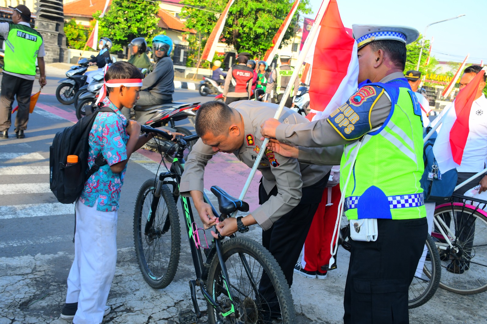 Kapolres Karanganyar AKBP Hadi Kristanto (tengah) membagikan bendera merah putih gratis ke pelajar di Jalan Lawu Karanganyar, Rabu (6/8/2025). (Rudi Hartono/Radar Solo)