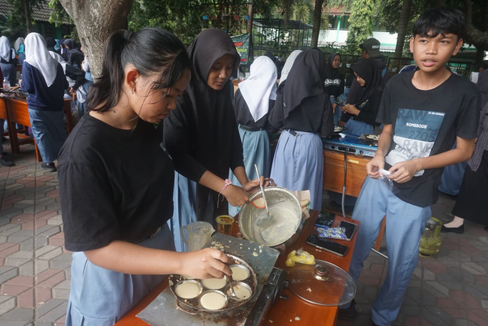 Ratusan siswa SMAN 1 Jatinom saat membuat kue apem di halaman sekolah setempat, Kamis (7/8/2025). (Angga Purenda/Radar Solo)