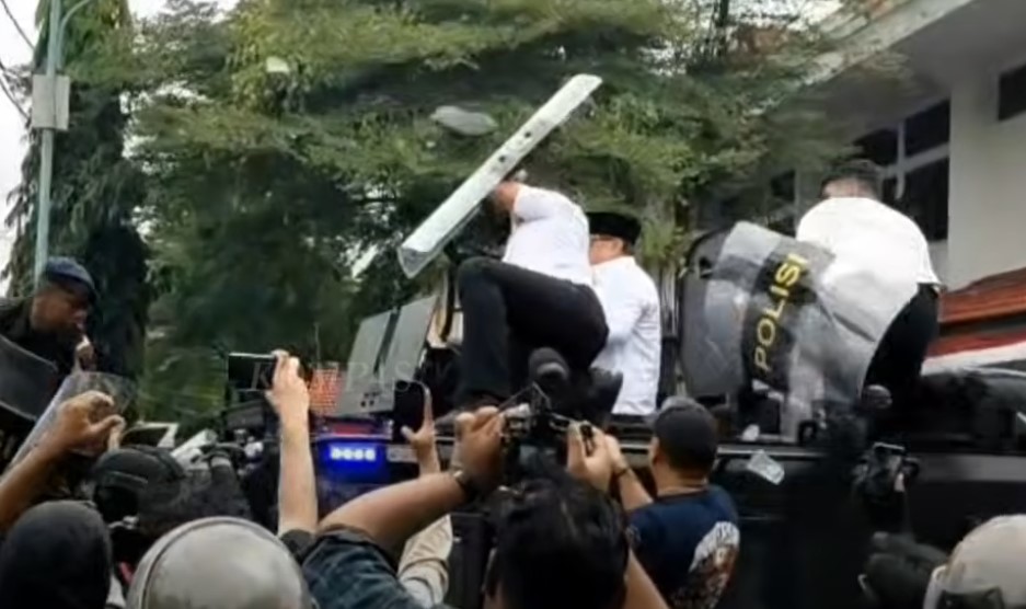 Aparat melindungi Bupati Sudewo menggunakan tameng dari lemparan sandal massa, Rabu (13/8/2025).