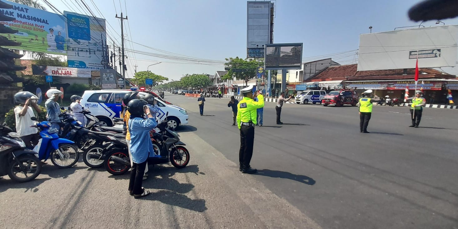 Polisi dan pengendara berhenti sejenak untuk hormat bendera detik-detik proklamasi di simpang empat Papahan, Karanganyar, Minggu (17/8/2025). (Rudi Hartono/Radar Solo)