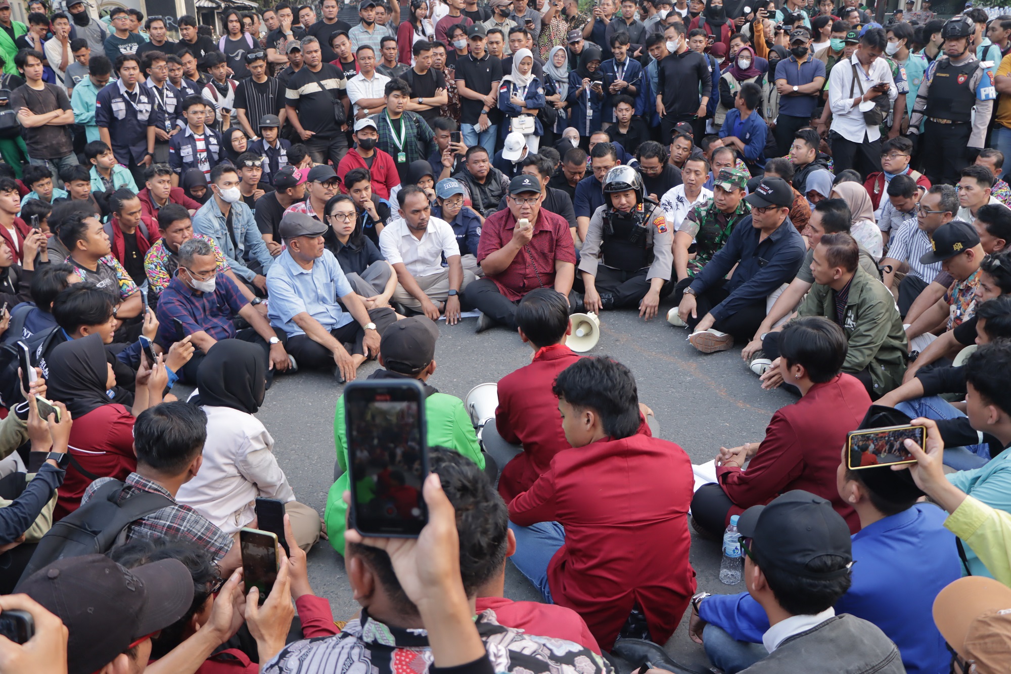 Ketua DPRD Kota Solo Budi Praseyo duduk lesehan bersama massa pendemo, Senin sore (1/9). (M Ihsan/Radar Solo)