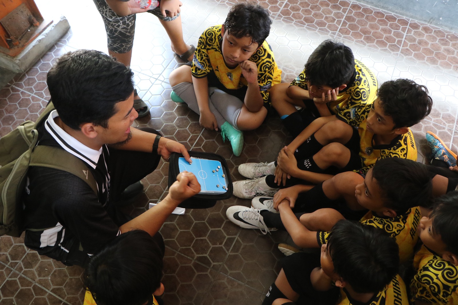Pelatih futsal merancang taktik sebelum bertanding.