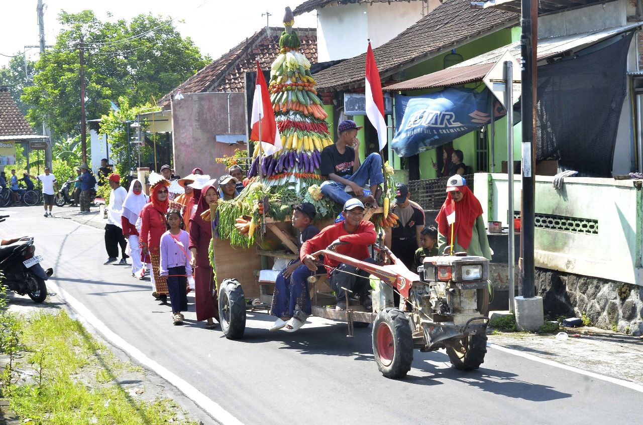 Gunungan hasil bumi yang ditarik menggunakan traktor dalam kirab budaya di Desa Gombang, Sawit, Boyolali, Minggu (28/9/2025).