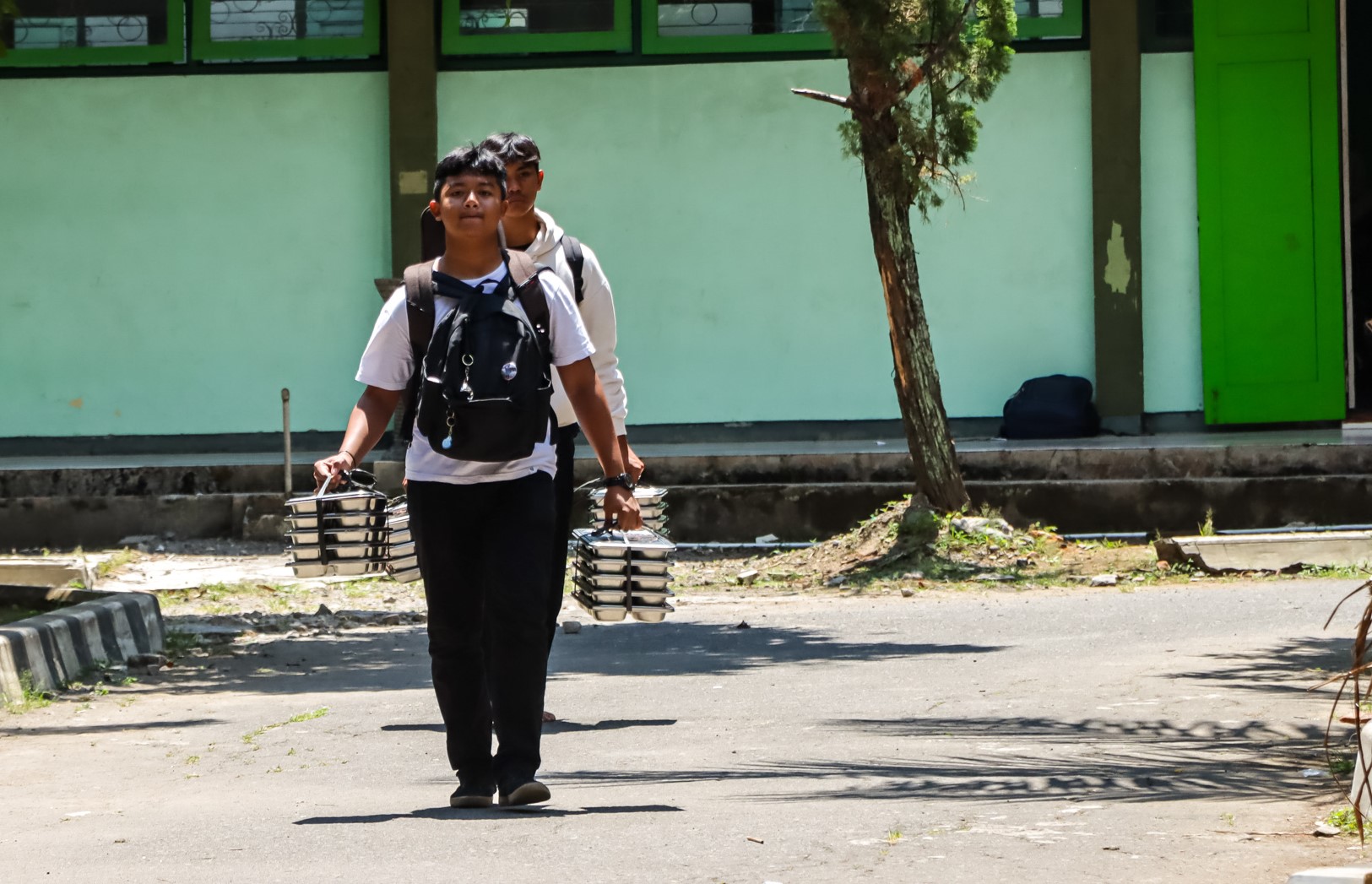 Siswa di Solo membawa ompreng berisikan menu MBG untuk dibagikan ke murid lainnya.