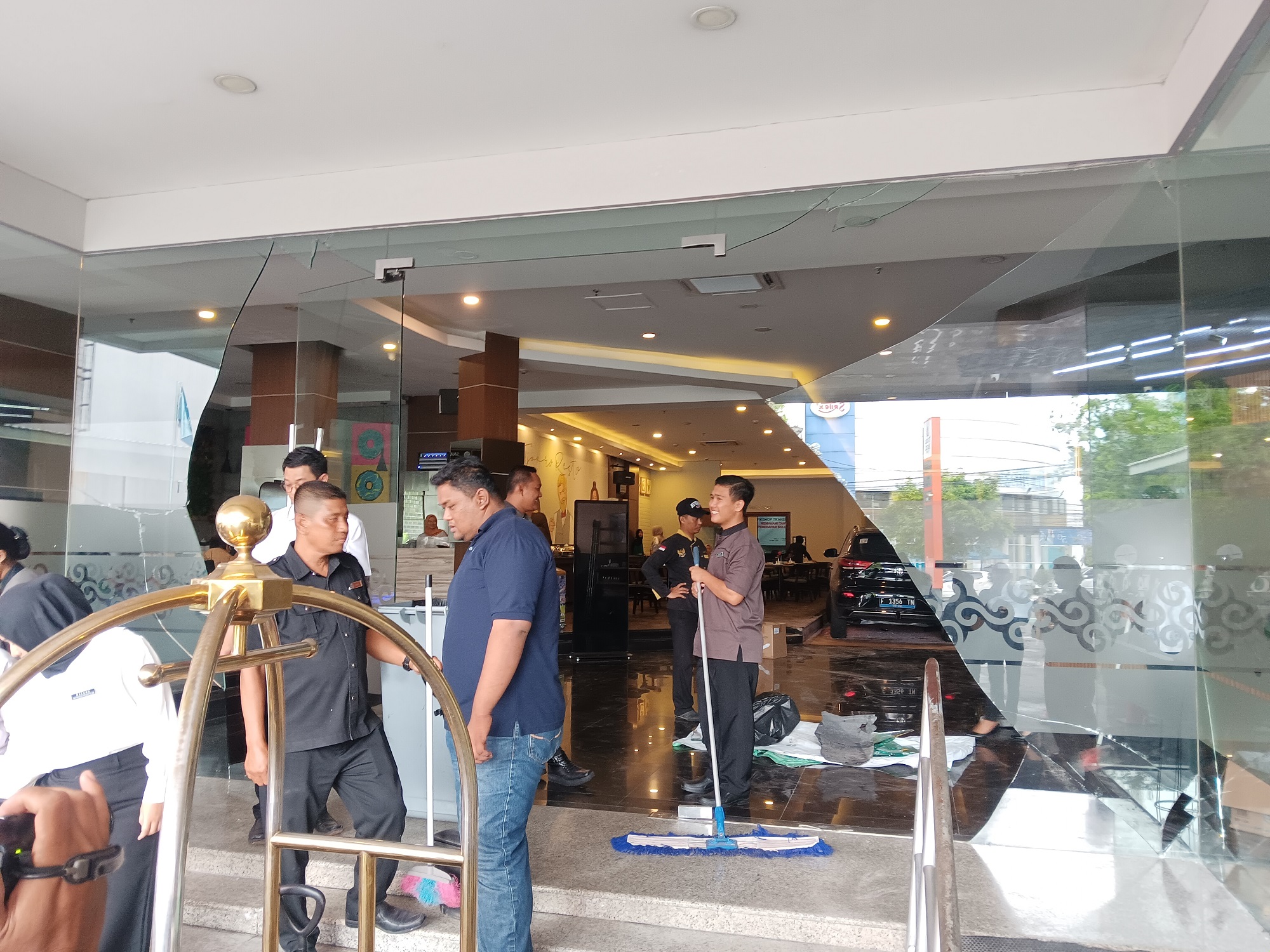 Petugas hotel saat melakukan pembersihan terhadap pintu masuk Tjokro Hotel Klaten yang ditabrak mobil. (Angga Purenda/Radar Solo)