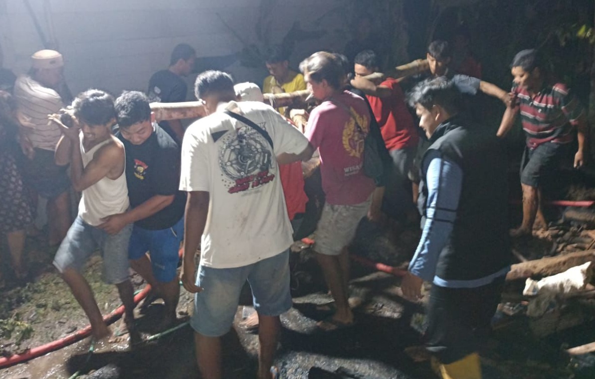 Warga menggotong sapi yang mati terpanggang akibat kandangnya terbakar, Kamis (30/10/2025) petang.