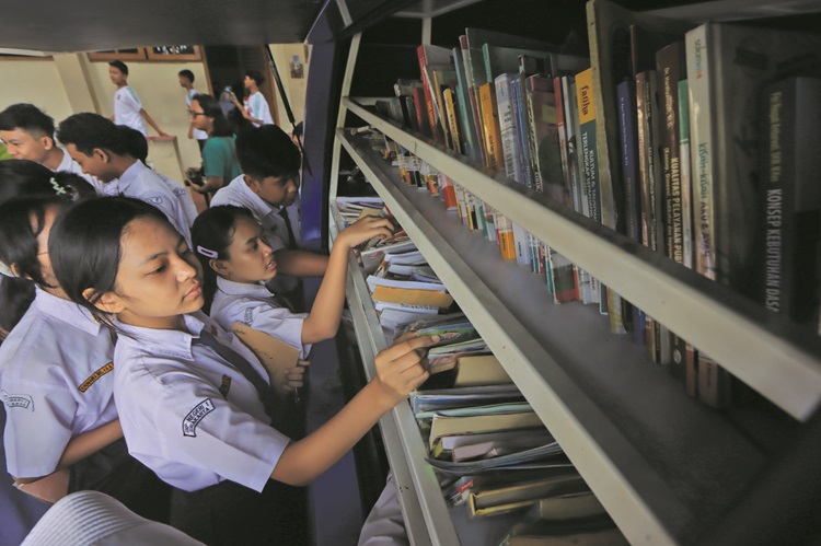 Pelajar salah satu SMP negeri di Kota Solo membaca koleksi buki di perpustakaan keliling yang mampir ke sekolah mereka, belum lama ini.