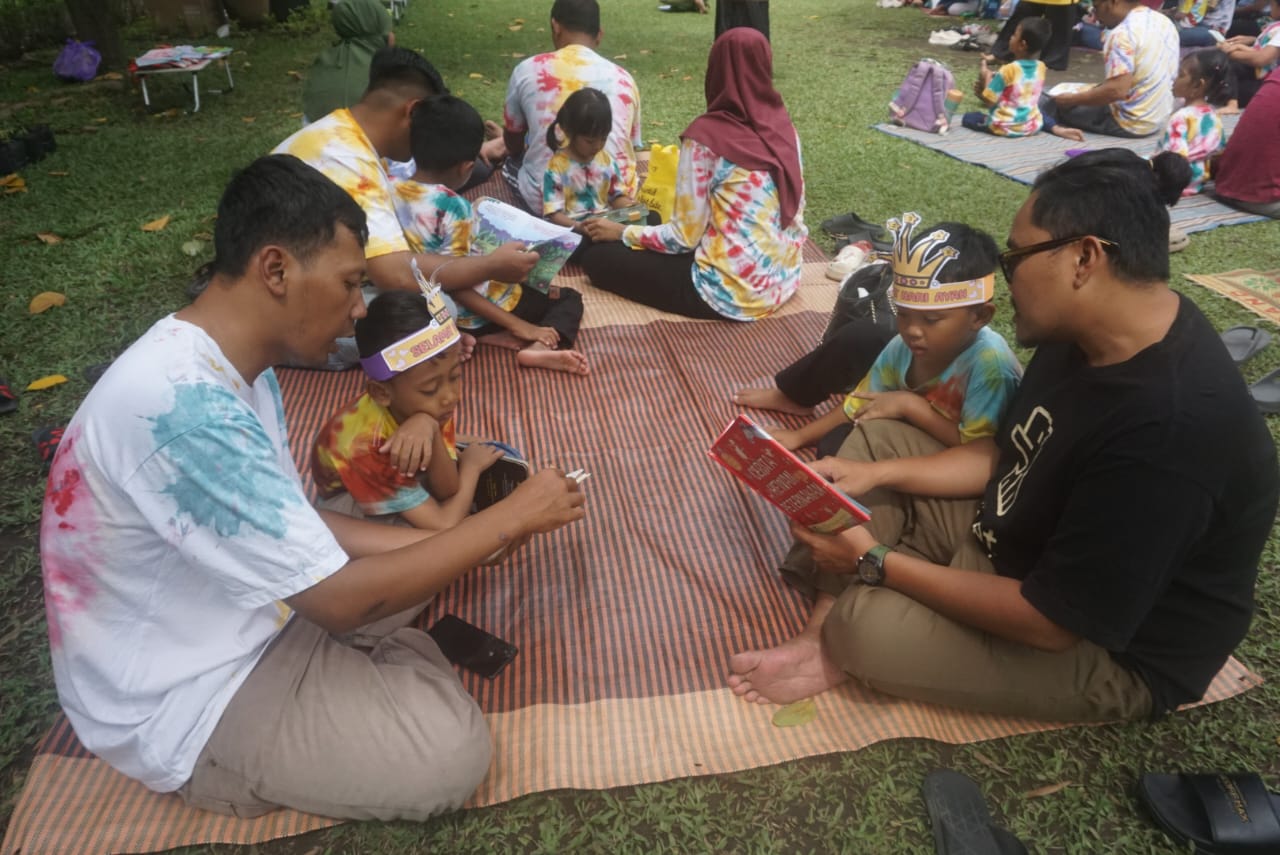 Aksi ayah di Klaten yang bacakan buku cerita untuk anaknya di Taman Lampion, Kelurahan Bareng Lor, Klaten Utara, Klaten, Sabtu (22/11/2025).