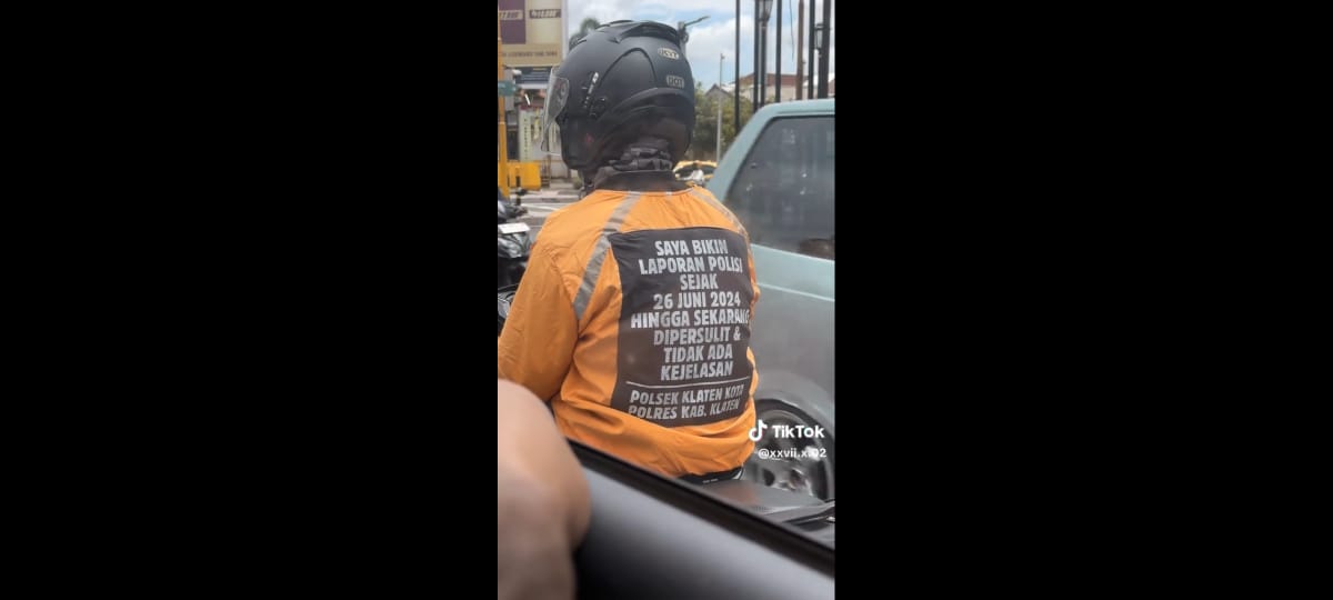 Seorang pengendara sepeda motor mengenakan jaket yang bertuliskan curhatan soal laporan ke Polsek Klaten. (Video Dokumentasi RichGirl)
