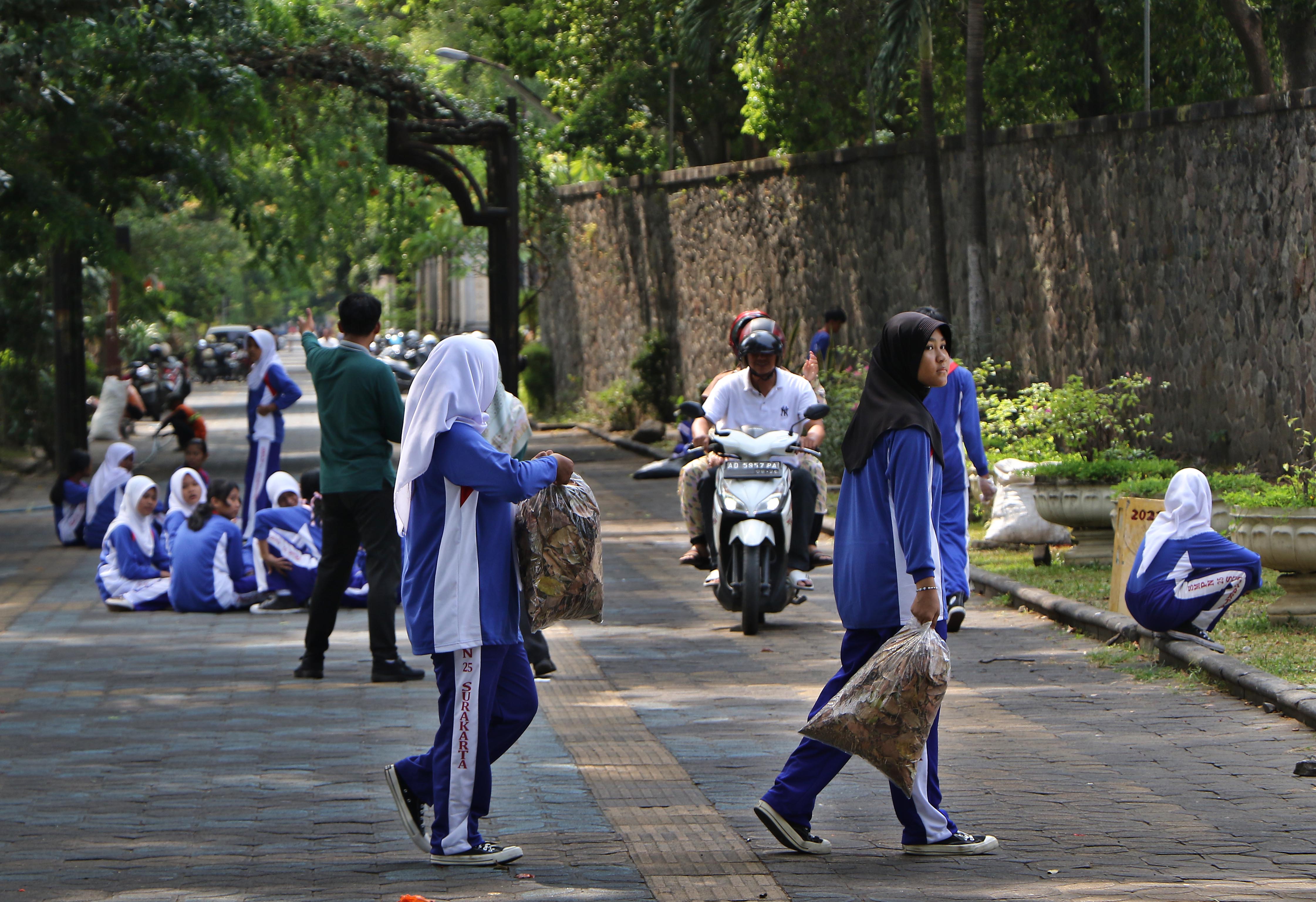 Siswa SMP di Kota Solo sedang membersihkan sampah di city walk. (Arief Budiman/Radar Solo)