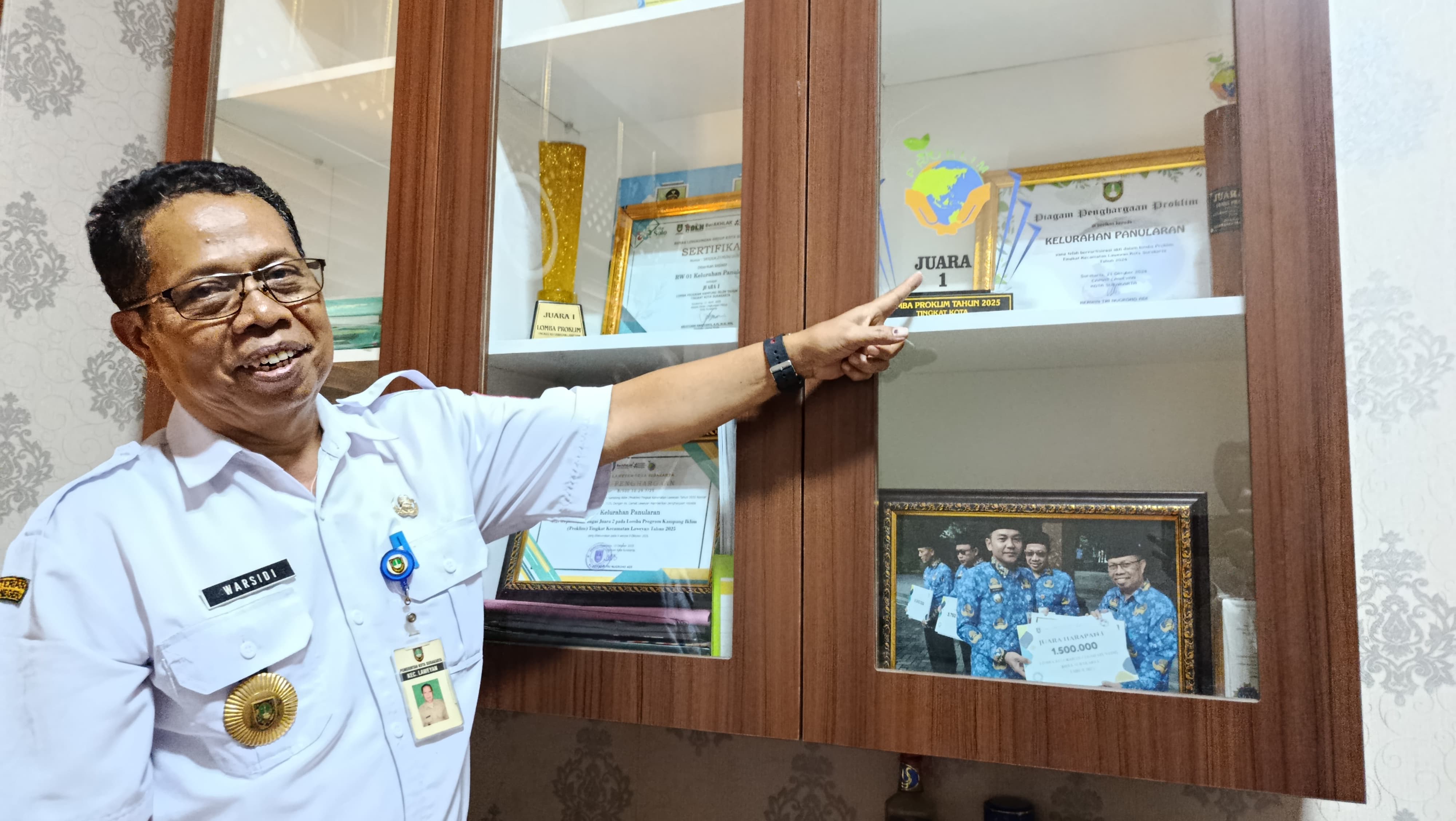 Lurah Panularan Warsidi tunjukkan trofi juara 1 Proklim Tingkat Kota.