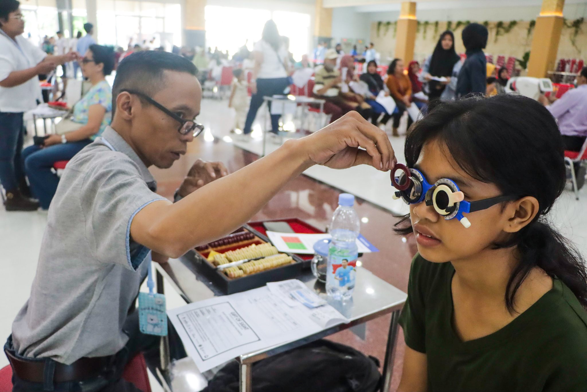 Penerima manfaat dites matanya dengan phoropter saat pembagian 1.500 kacamatan gratis di Gedung PMS Solo, Selasa (16/12).