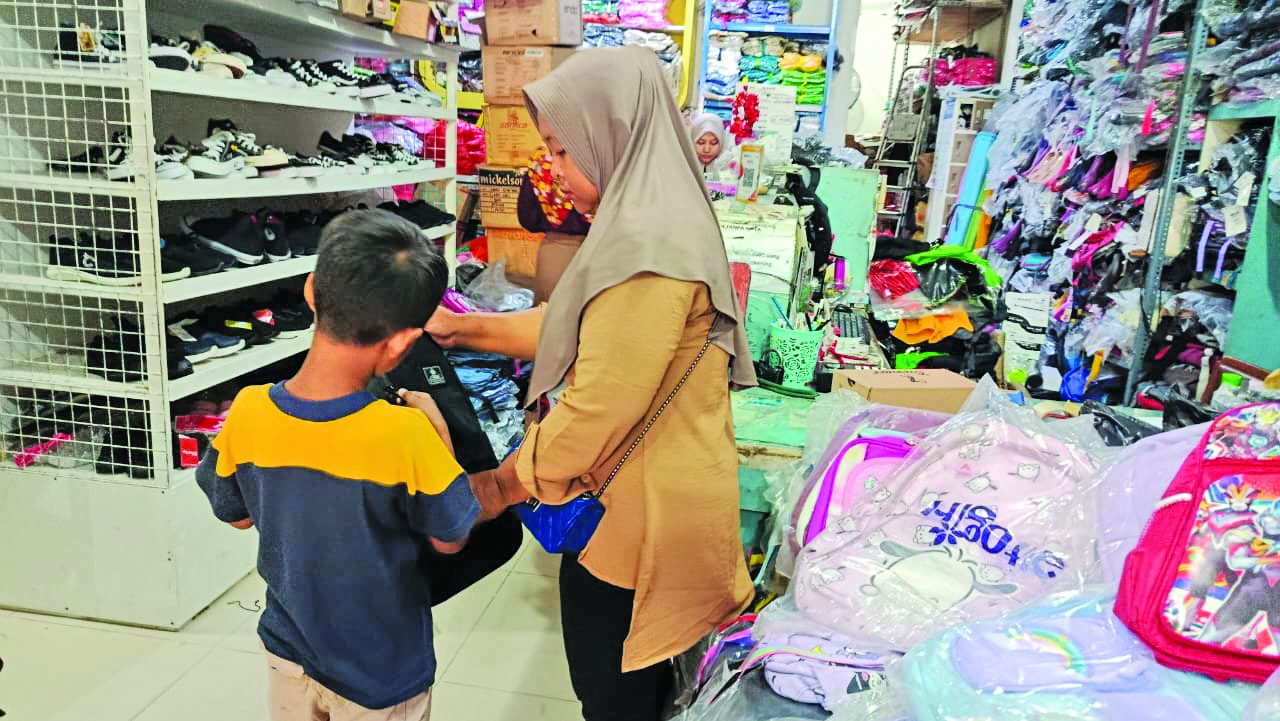 MENCOBA: Seorang tua berbelanja peralatan sekolah, belum lama ini.