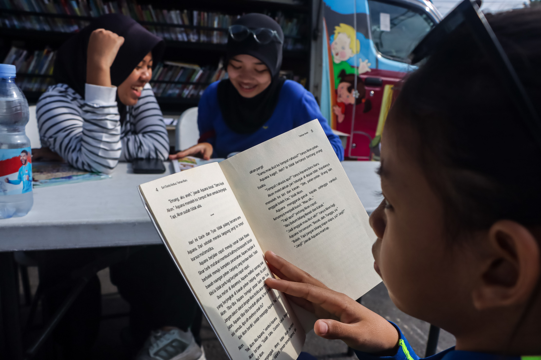 Anak-anak membaca buku koleksi Mobil Perpustakaan Keliling Dinas Perpustakaan dan Kearsipan (Dispersip) Kota Solo di CFD Solo, Minggu pagi (21/12),