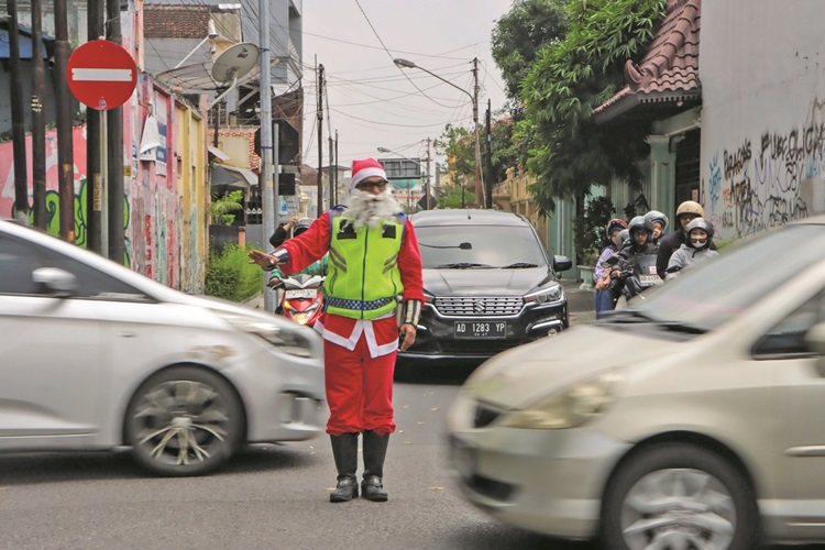 Martin Hidungoran, supeltas yang biasa bertugas di simpang empat Jalan Dr. Cipto Mangunkusumo, Sriwedari, Solo mengenakan kostum Sinterklas, Rabu (24/12).