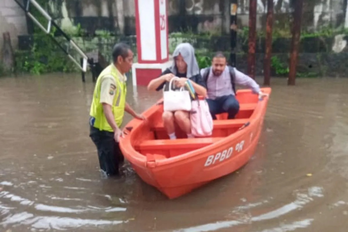 Petugas mengevakuasi warga yang rumahnya terendam banjir di Jakarta, Senin (12/1/2026).