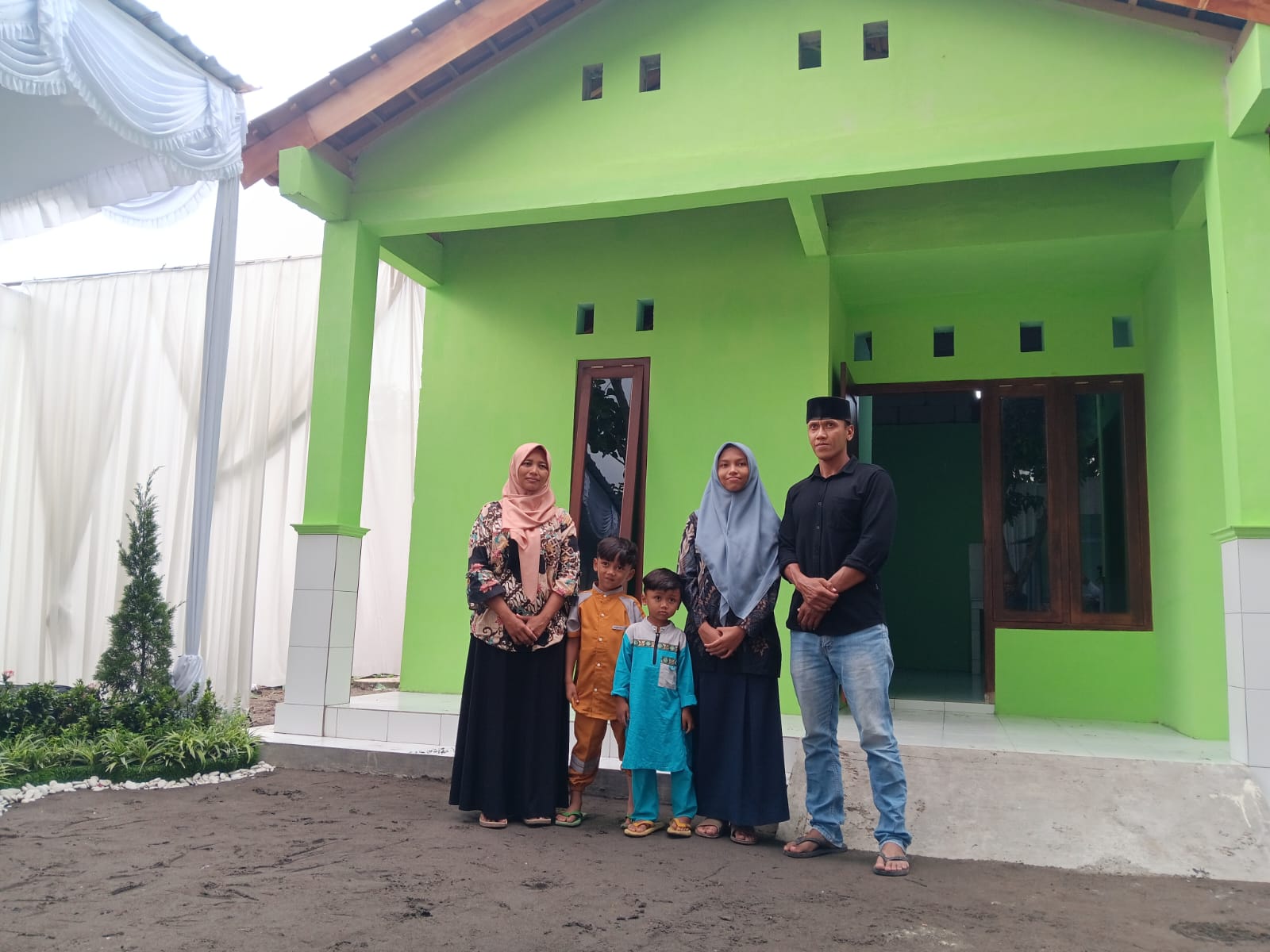 Hermiyati bersama keluarga di depan rumah yang direnovasi. (Angga Purenda/Radar Solo)