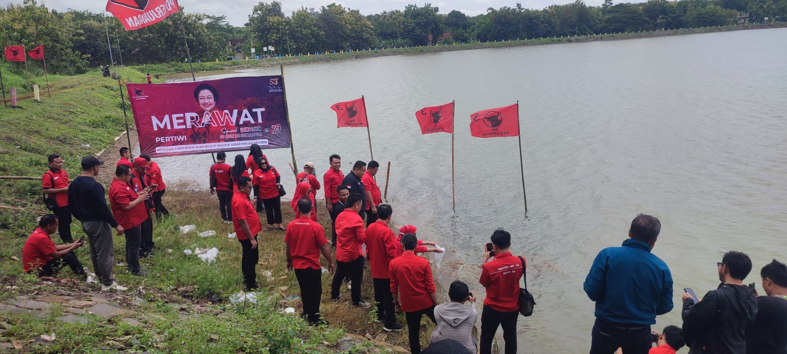 Pengurus dan kader DPC PDIP Sragen melepas benih ikan di Waduk Kembangan, Karangmalang, Sabtu (25/1/2026). (Ahmad Khairudin/Radar Solo)