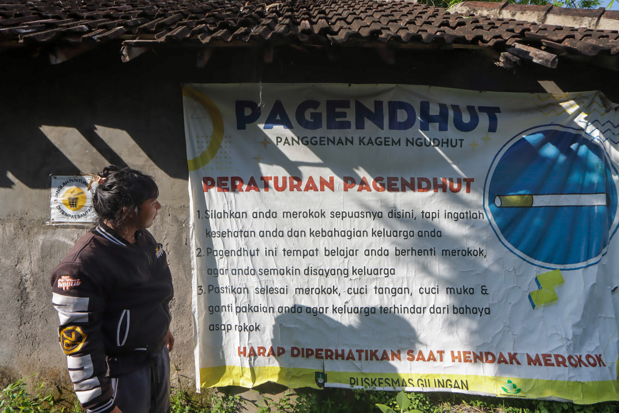 KEBIJAKAN: Seorang warga tengah melihat spanduk larangan merokok di Kampung Anti Rokok Gilingan Banjarsari.