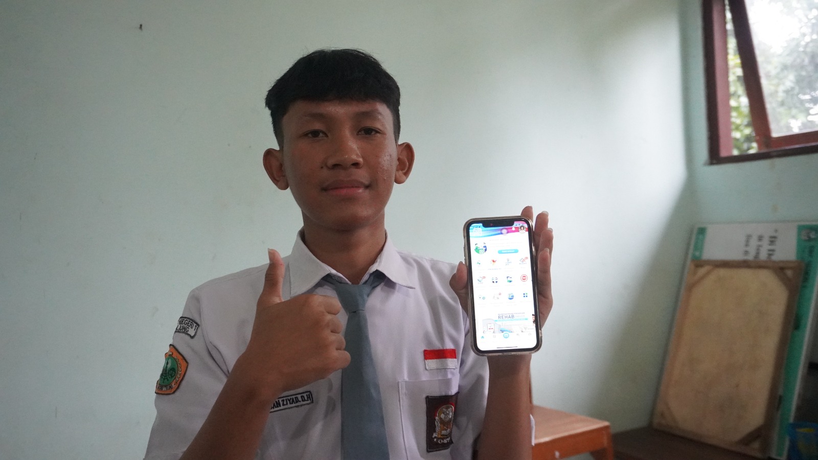 Peserta JKN dari SMK N 1 Tulung, Klaten Akhdan Ziyad Dafa Ulhaq yang sedang menunjukan aplikasi Mobile JKN.