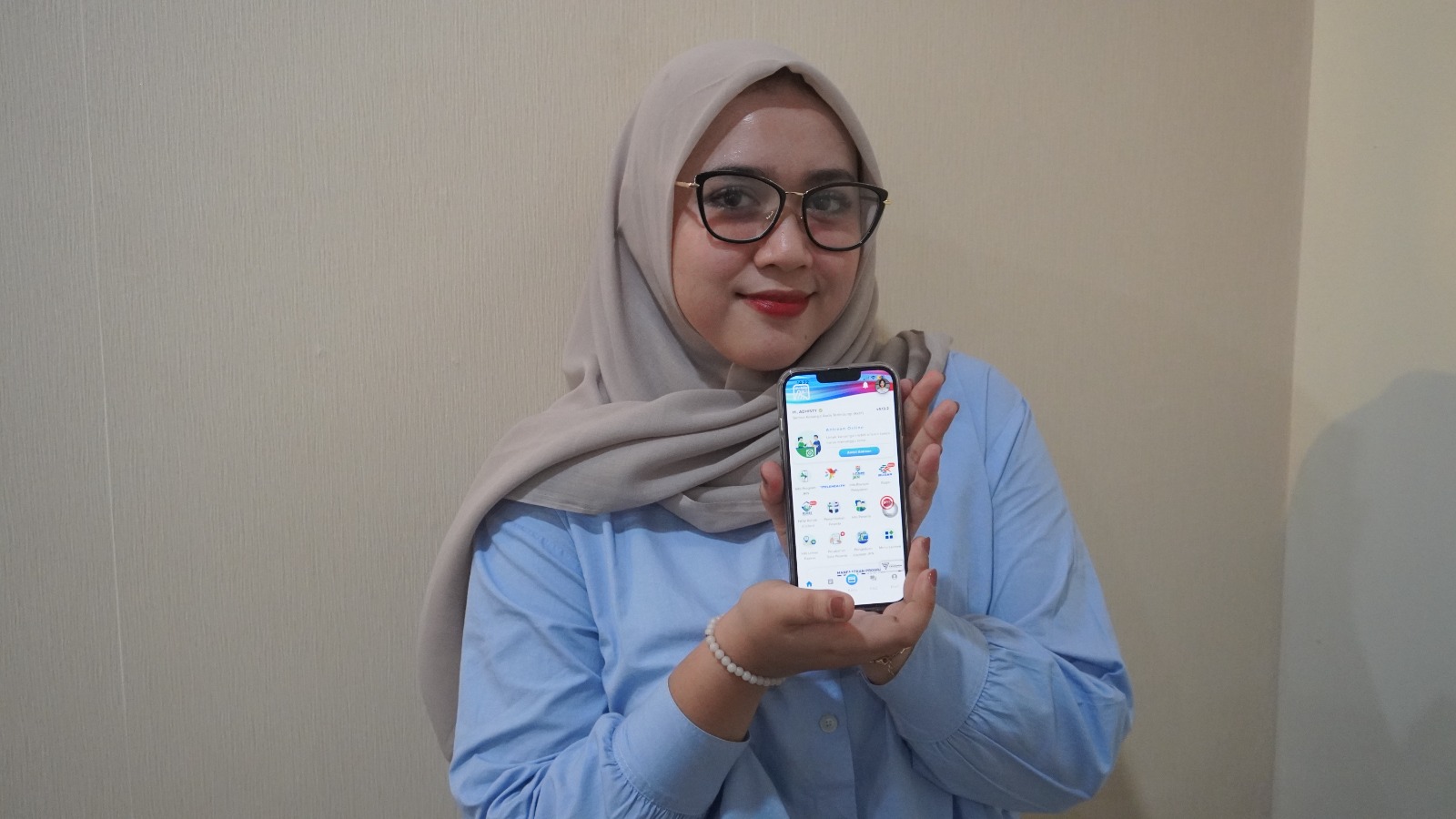 Adhisty menunjukan aplikasi Mobile JKN yang mempermudah akses kesehatan.