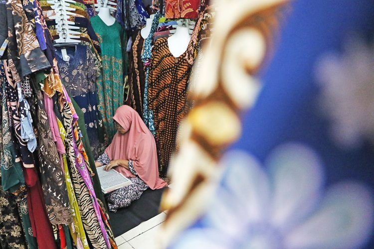 Seorang pedagang batik di Pasar Klewer Solo mengisi ibadah Ramadan dengan membaca Alquran di sela aktivitas berjualan di dalam kiosnya, Jumat (6/3).