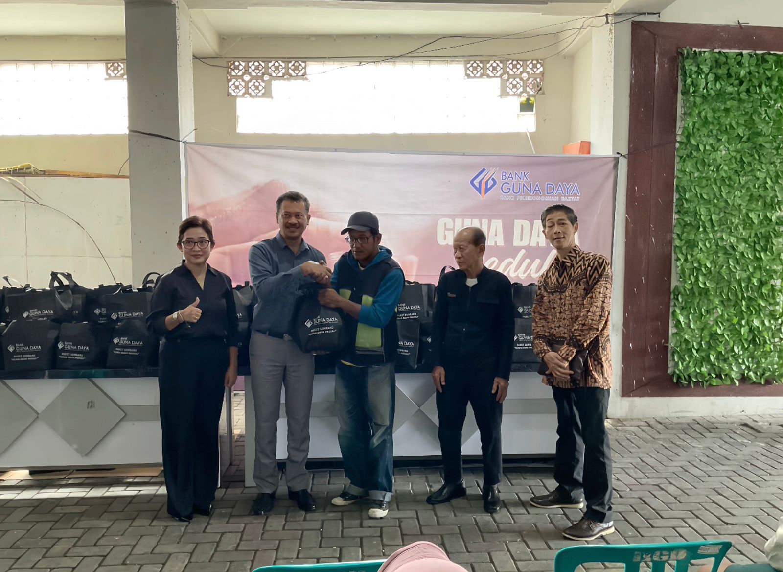 Direktur Utama Bank Guna Daya Arry Mardiyanto (dua dari kiri) memberikan bantuan sembako kepada masyarakat.