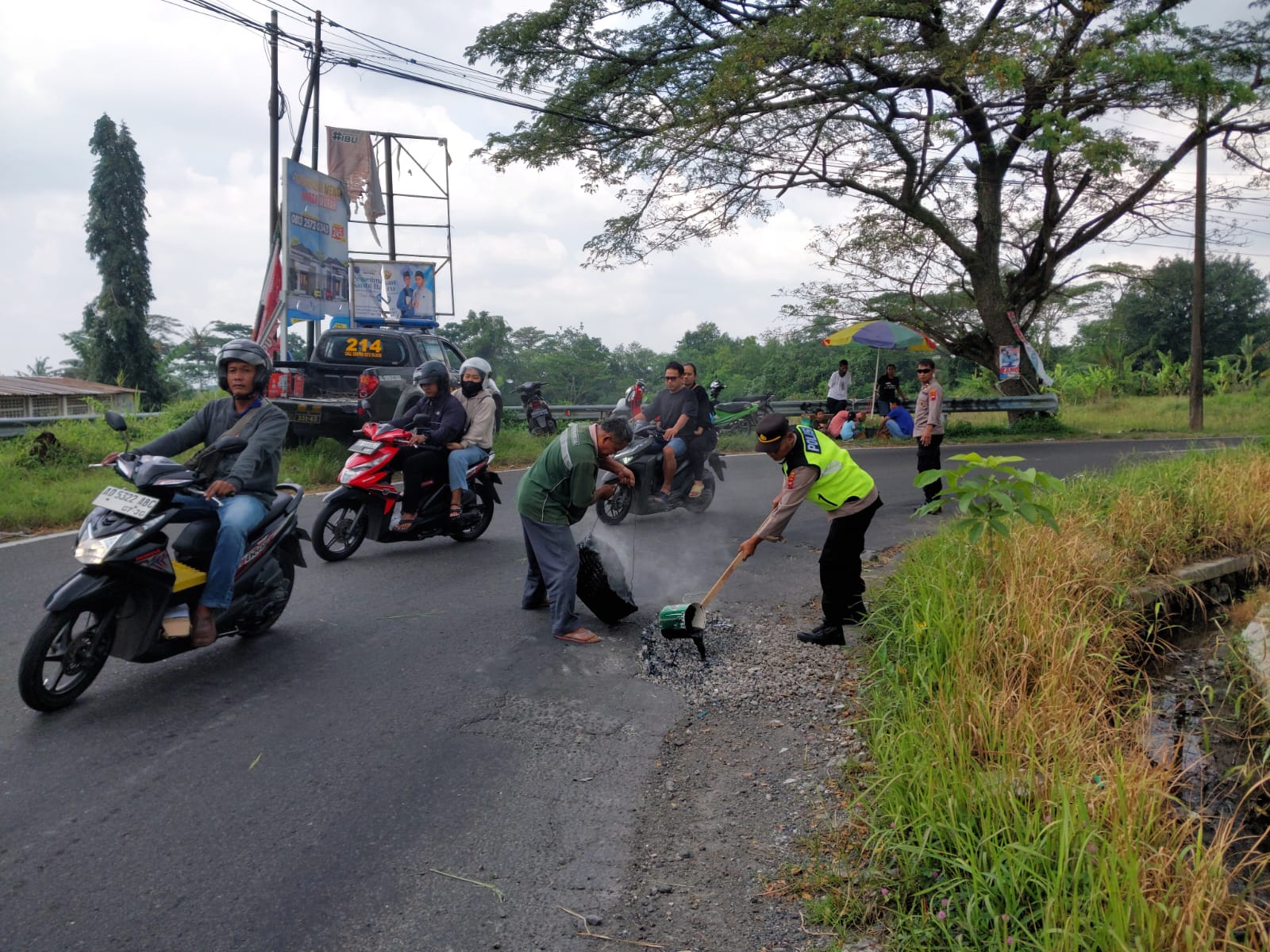 Jajaran Polsek Polanharjo dan relawan menambal lubang jalan yang menuju objek wisata.
