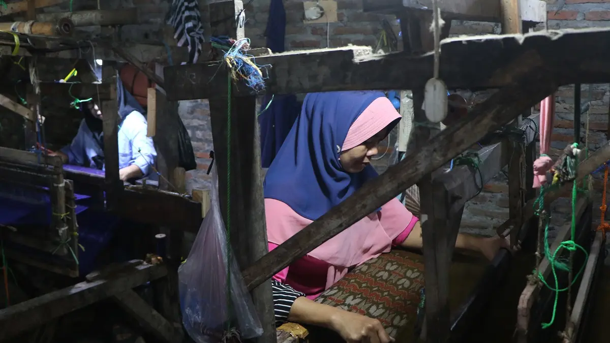Pekerja menyelesaikan produksi sarung tenun goyor dengan alat tenun bukan manual (ATBM) di industri rumahan Jalan Mojo, Kelurahan Semanggi, Kecamatan Pasar Kliwon, Solo.