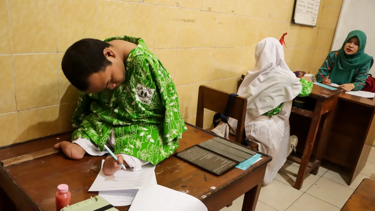 Siswa ABK SLB YPAC Solo mengerjakan soal Penilaian Sumatif Akhir Jenjang (PSAJ) di ruang kelas sekolah setenpat, Rabu (8/4). (M IHSAN/RADAR SOLO)