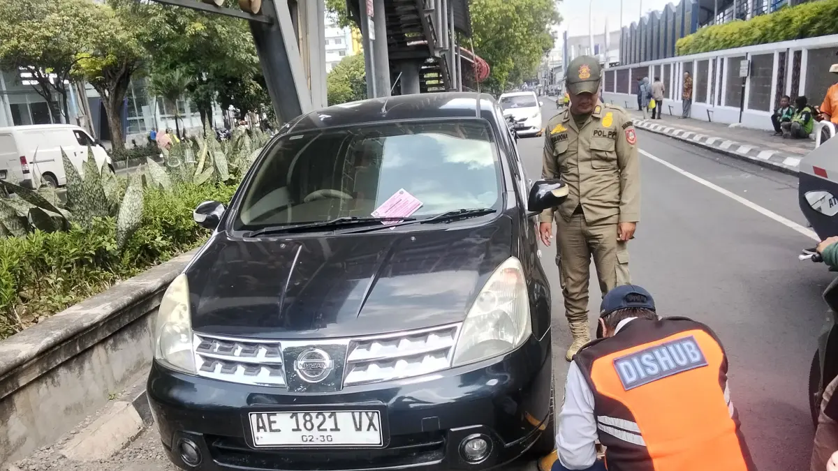 Petugas Dishub Kota Solo menggembok kendaraan yang nekat parkir di badan jalan. (A Christian/Radar Solo)